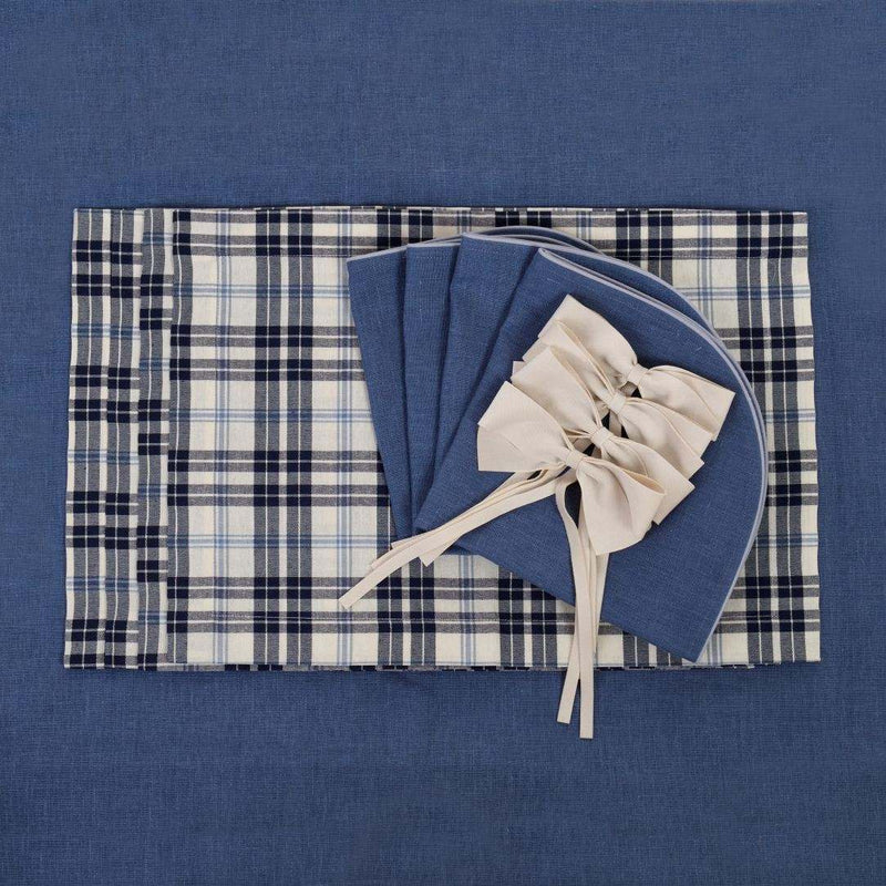 Cotton placemat with navy and light blue plaid on matching tablecloth with napkins ans bow napkin rings.