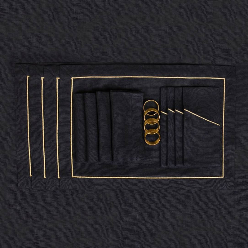 Black linen placemat with gold embroidered border with matching napkins and napkin rings.