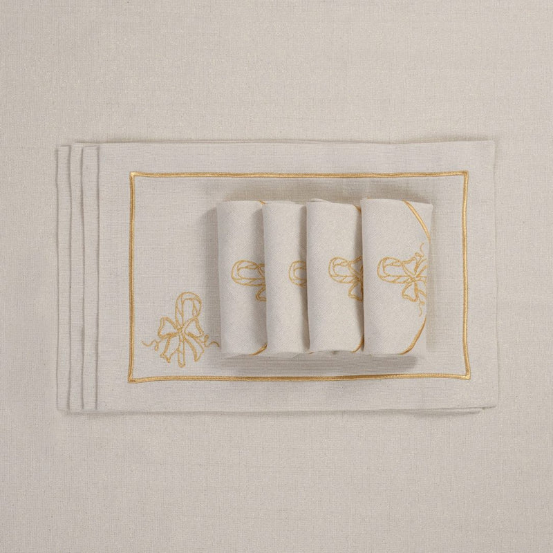 Folded light beige napkins with gold embroidered candy cane motif on matching tablecloth.