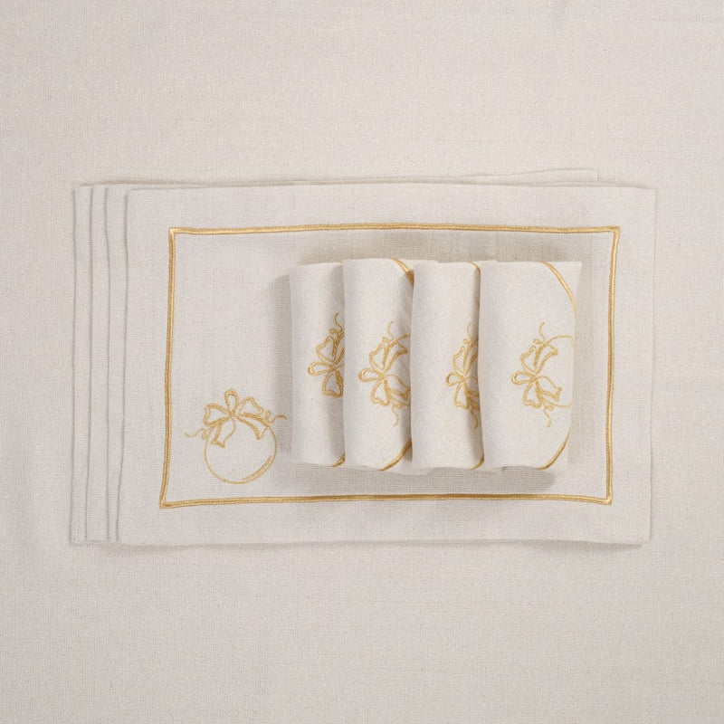 Folded light beige napkins with gold embroidered bauble motif on matching tablecloth.