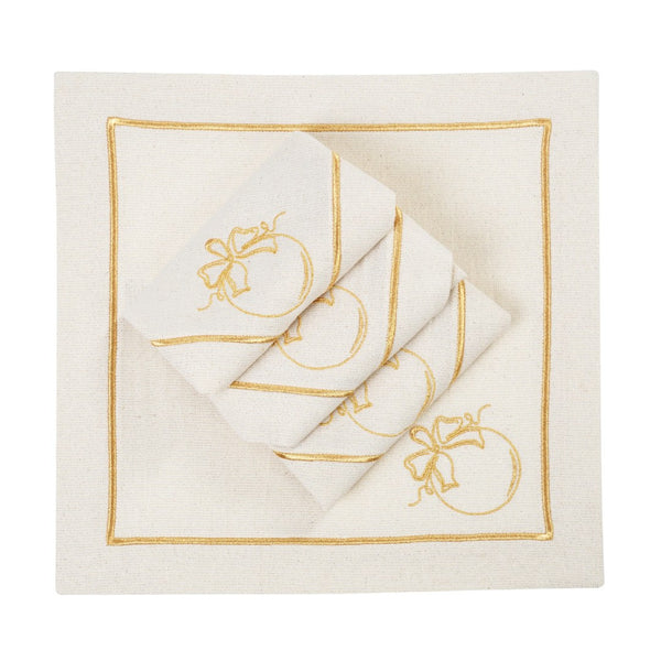 Folded light beige napkins with gold embroidered nauble motif on white background.