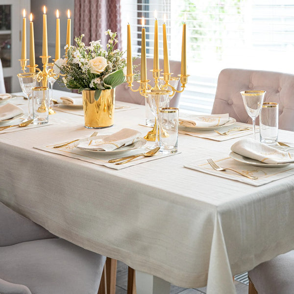 Luxurious Christmas table with light beige napkins with gold jingle bells embroidery.