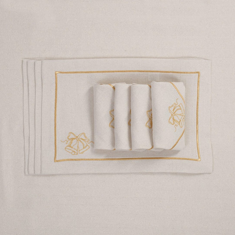 Folded light beige napkins with gold embroidered jingle bells motif on matching tablecloth.