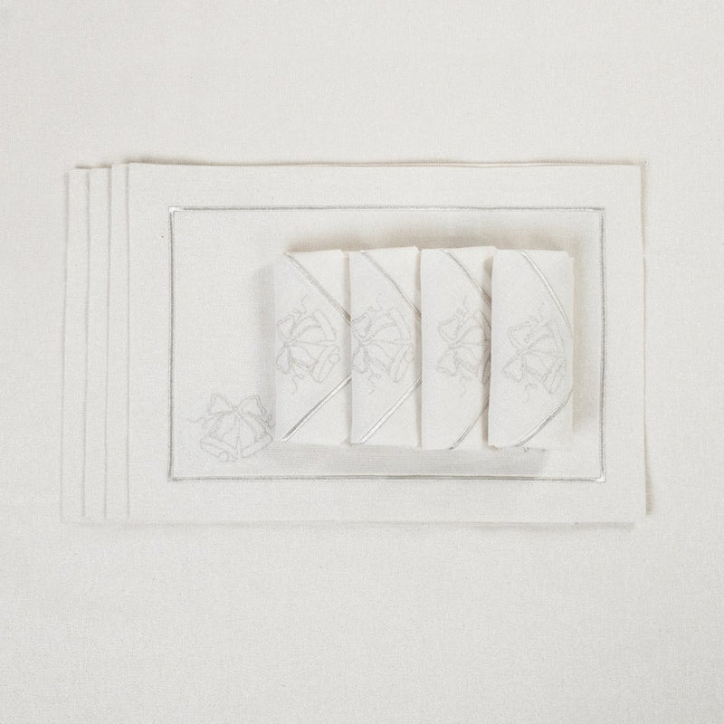 Silver lurex napkin with embroidered bell motif folded on matching tablecloth.