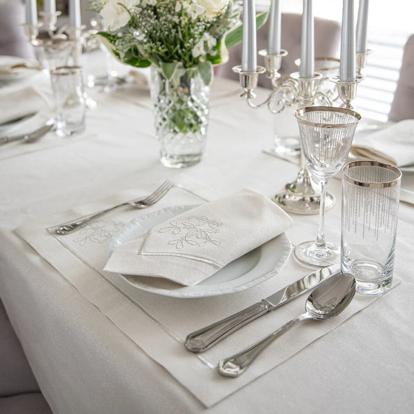 Mistletoe Silverline embroidered napkin styled on Christmas table with festive decor and sparkling accents.