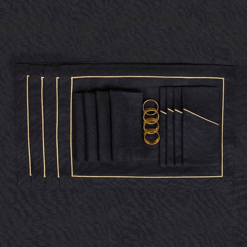 Black linen napkins with gold napkin rings on a black tablecloth.