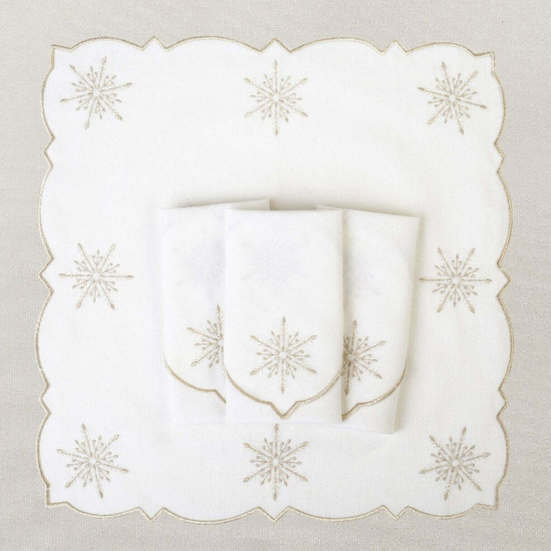 White cotton napkin with silver embroidered snowflakes details folded on silver tablecloth.