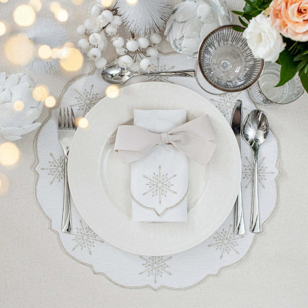 White cotton napkin with silver embroidered snowflakes details styled with silver bow on plate.