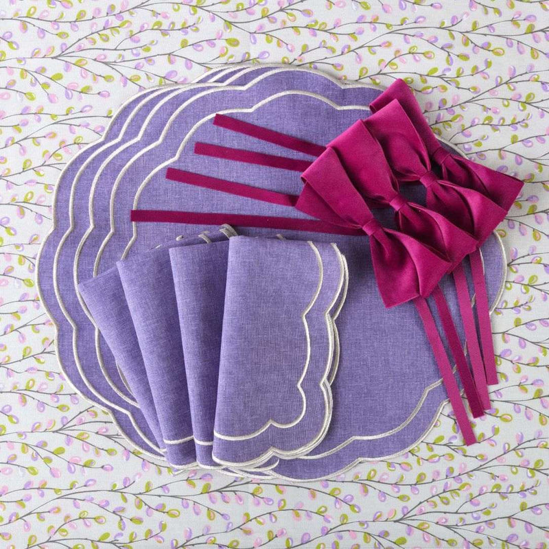 Folded Purple Petali embroidered napkin with wave border top view.