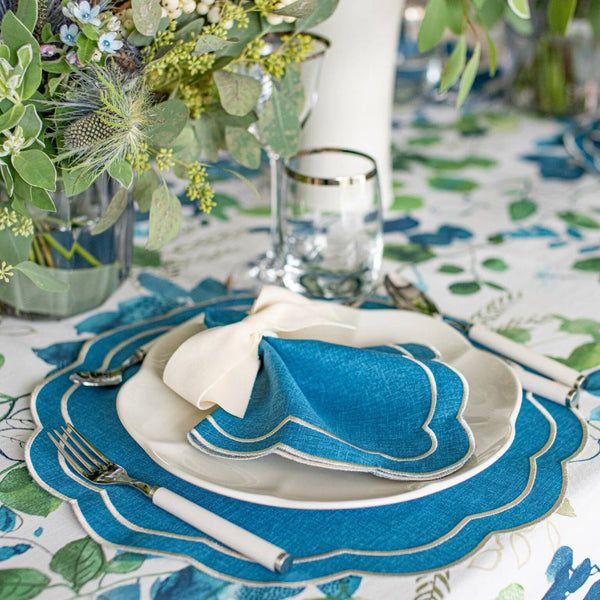 Blue Petali napkins with wave borders and ecru embroidery along the borders styled on clasic table setting, sold at Amiramour.