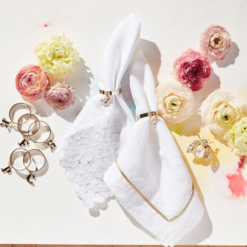 White linen napkin with embroidered hydrangea by Joanna Buchanan styled with gold napkin ring