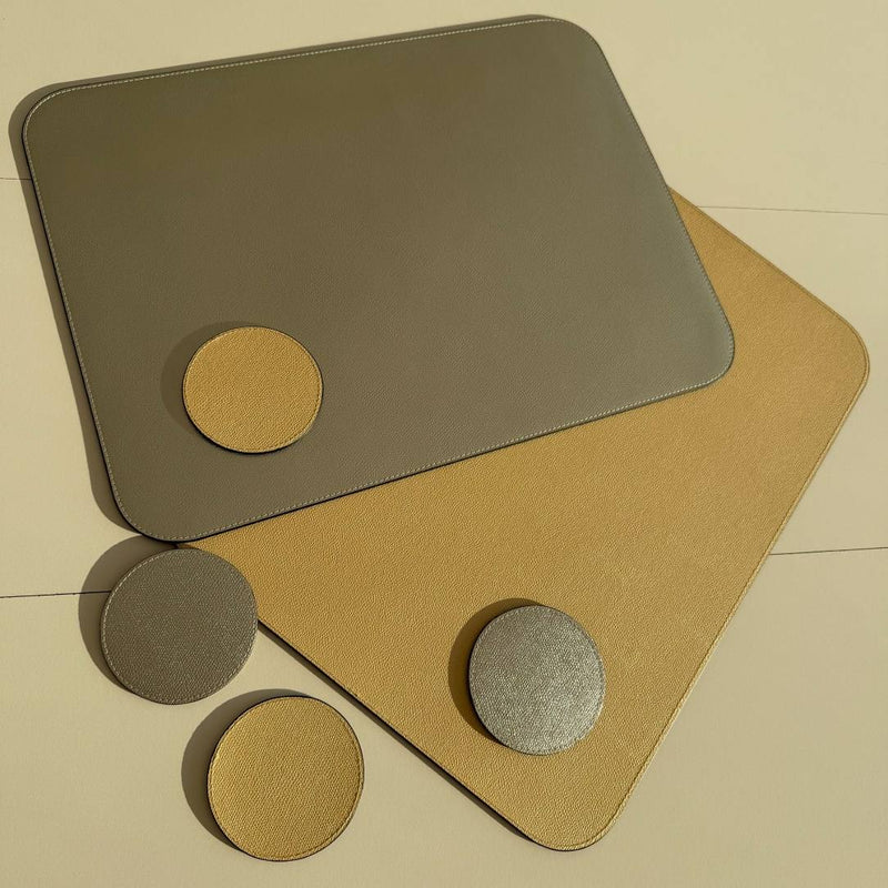 Reversible leather placemat in metallic gold and silver by Giobagnara with matching coasters.