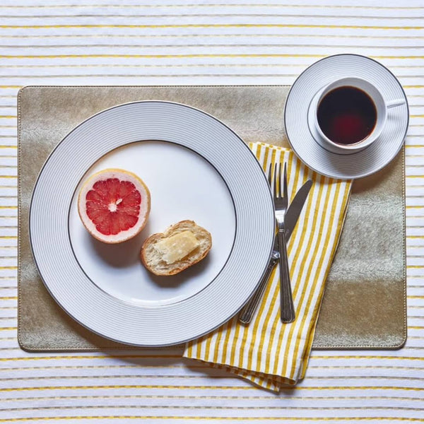 Rectangular reversible faux leather placemat in silver and gold on breakfast table.