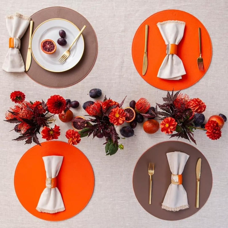 Reversible placemat in taupe and orange faux leather styled on fall luxe tablescape.