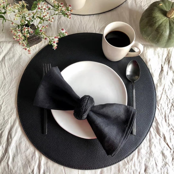 Reversible placemat in black and off-white faux leather styled black side.