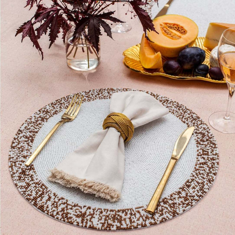 Von Gern Home Splatter placemat in bronze and white beads styled with gold napkin ring.
