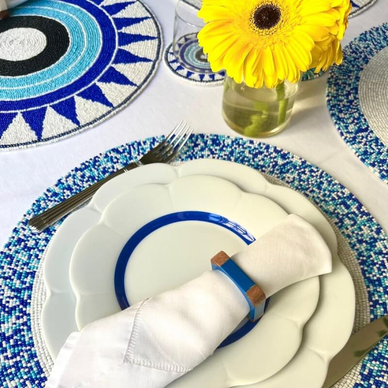 Blue hand-beaded placemat with geometric circle pattern on summer table.