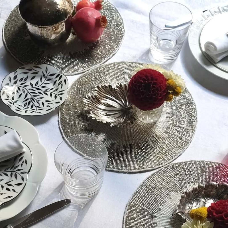 Celebration placemat with silver beaded border and white center on luxury tablescape.