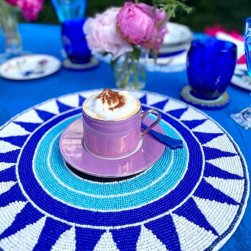 Blue hand-beaded placemat with tribal pattern on outdoor table.