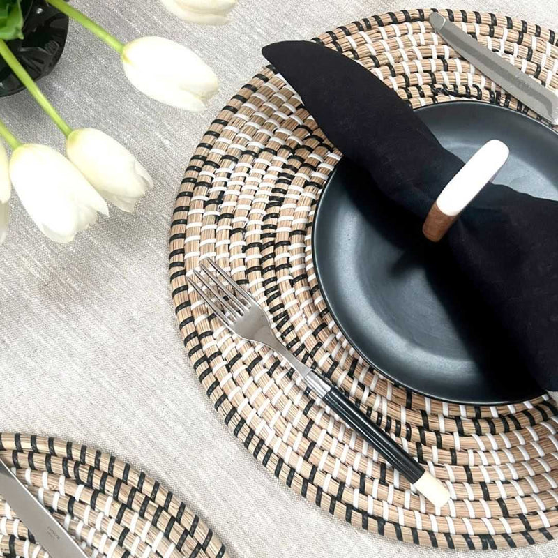Terra woven placemat in seagrass styled with black napkin and white napkin ring side view.