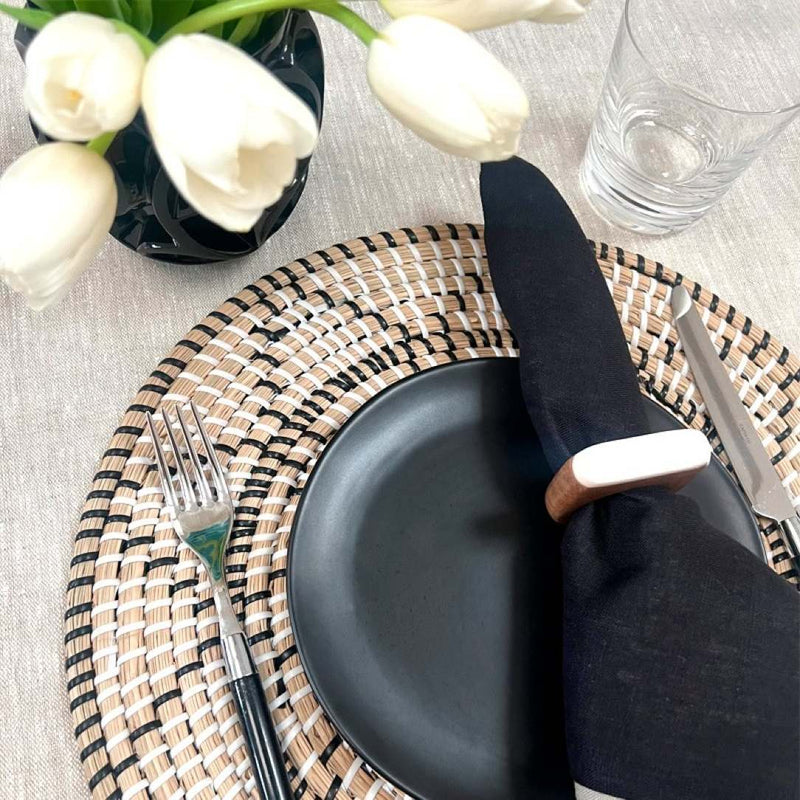Terra woven placemat in seagrass styled with black napkin and white napkin ring next to tulips.