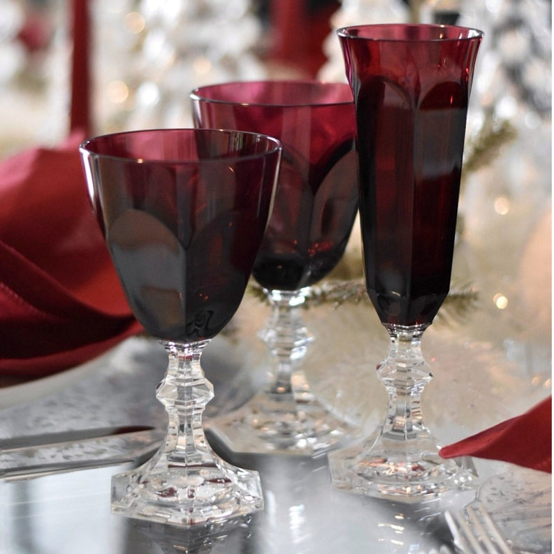 Three red wine glasses on a table with a blurred festive background