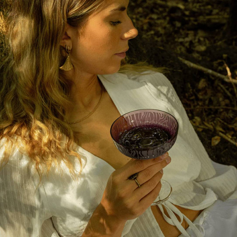 Woman holding a luxury crystal Champagne Coupe in Amethyste pink-purple from Alice Collection