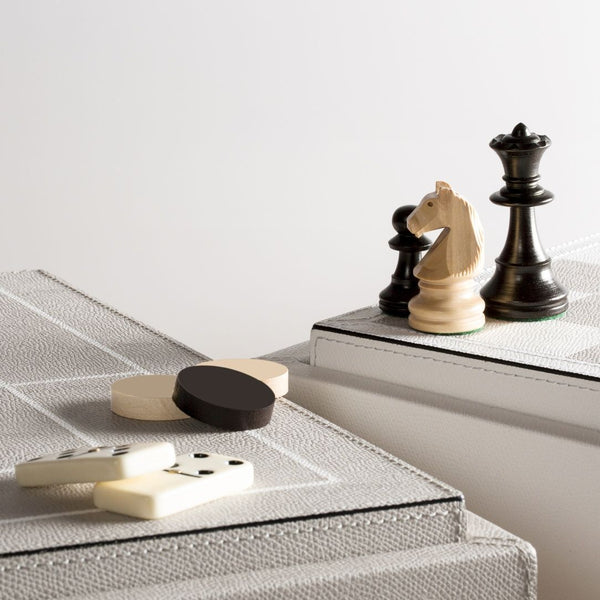 Close-up of Giobagnara Quadruple Game Box showing luxury boxwood chessmen, draughts, and domino pieces on fine leather surface.