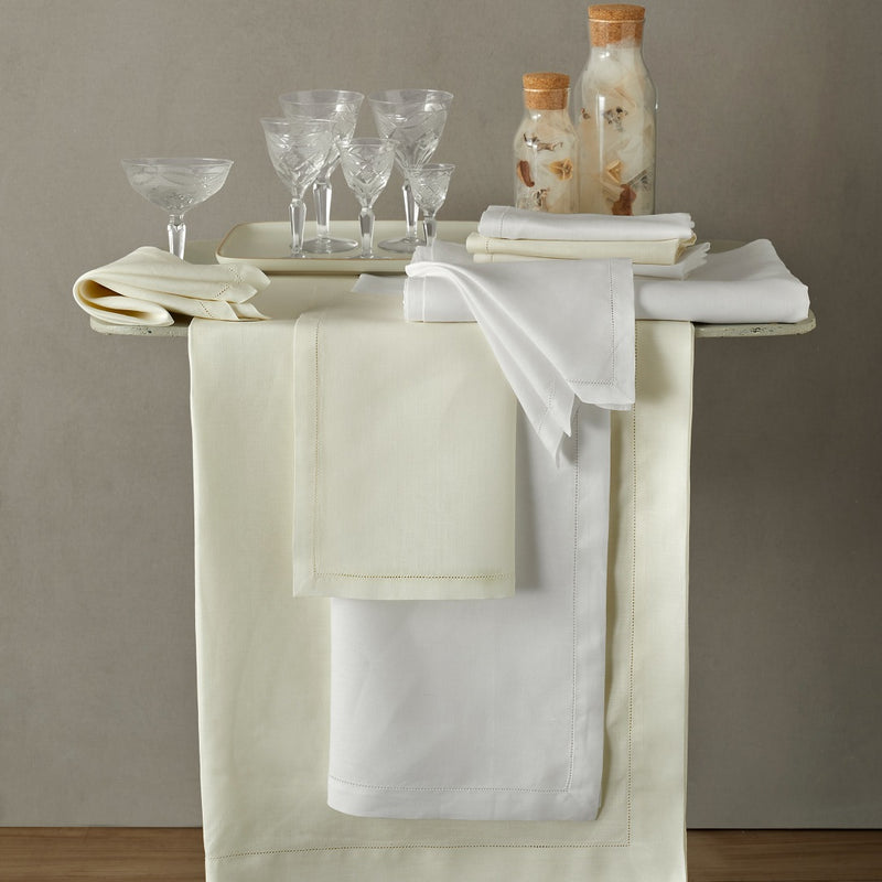 White and ivory linen napkins folded on matching tablecloth and runners.