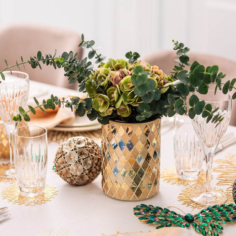 Decorative table setting with a vase of flowers and glasses on a white tablecloth.