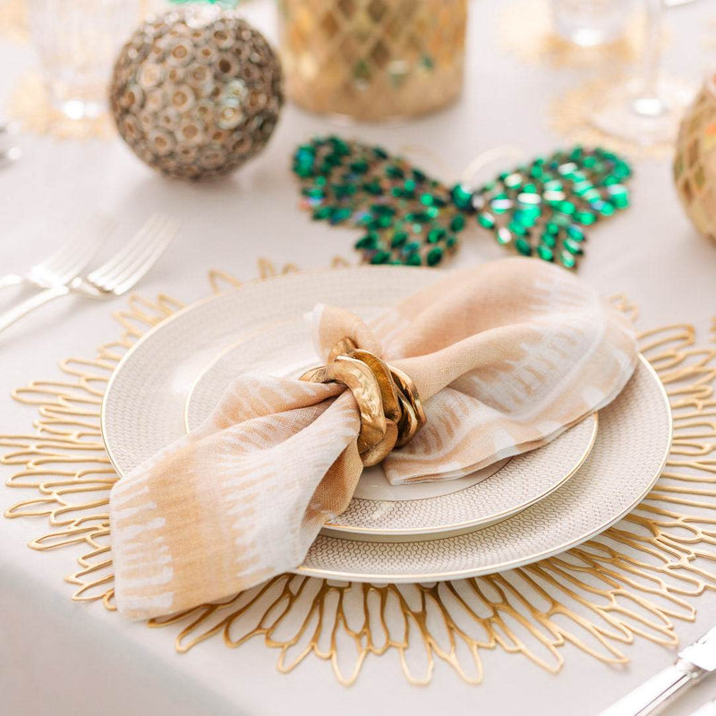 Decorative table setting with plates, napkin, and gold accents on a white surface.
