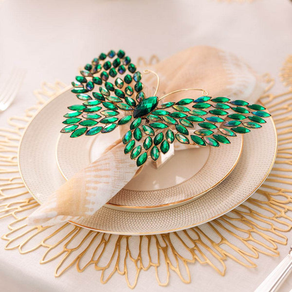 Bejewelled butterfly napkin ring in gold with green crystals on elegant gold-rimmed dinnerware from Amiramour’s Butterfly Effect themed table décor set.