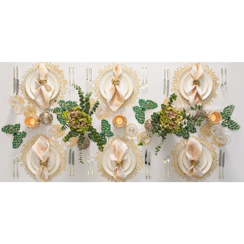 Elegant table setting with gold plates, napkins, and floral centerpieces on a white tablecloth.