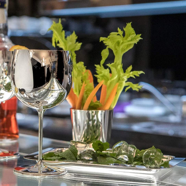 Luxury balloon glass silver plated by Greggio – handcrafted Italian tableware with a blurred bar setting in the background