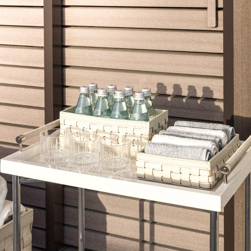 Outdoor setting with a table holding bottles, glasses, and folded cloths against a wooden wall.