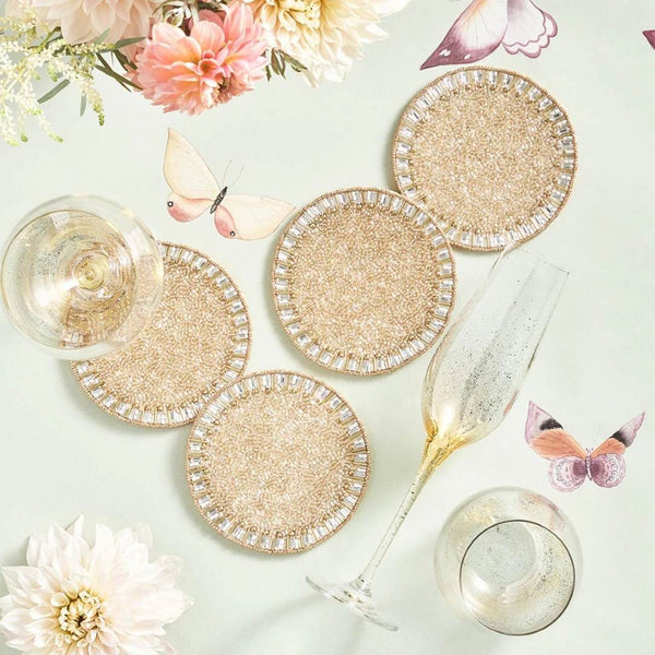 Set of glittery coasters with glasses and flowers on a light surface