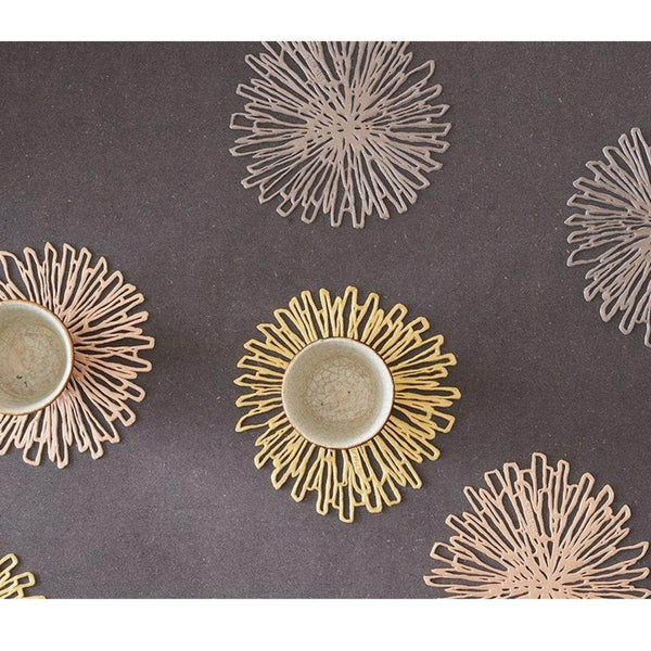 Decorative gold coasters with a floral pattern on a gray surface