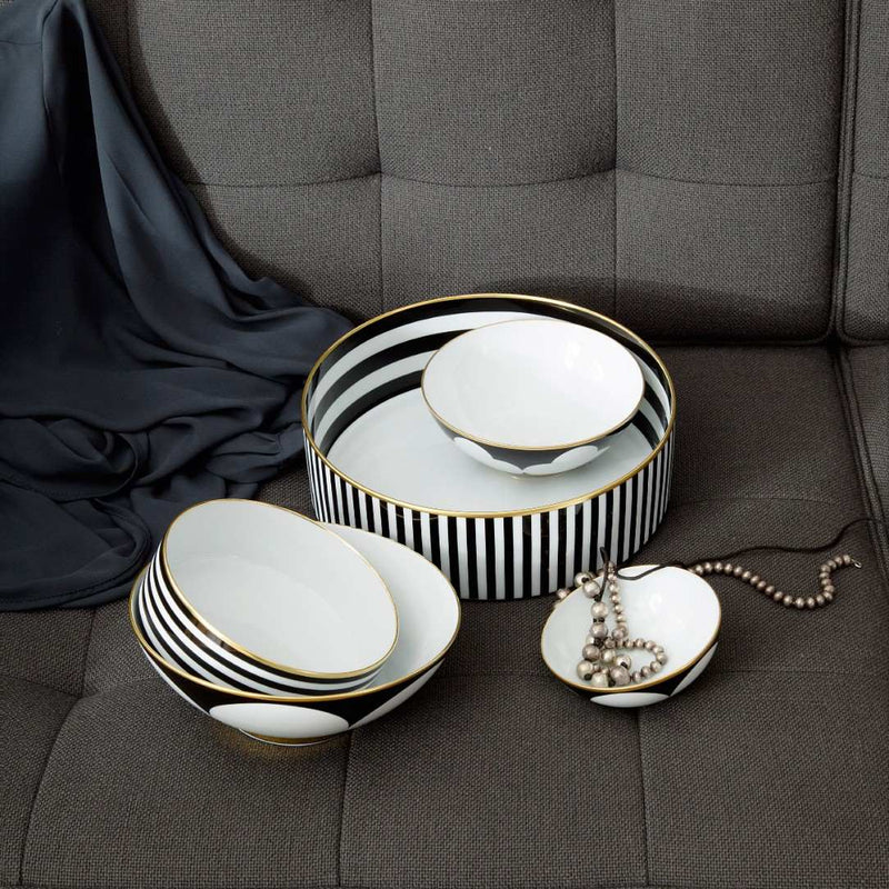 Set of black and white ceramic dishes with gold trim on a gray surface