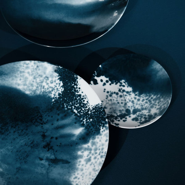 Close-up of Indigo ocean-inspired bread and butter plate from Abysses collection by Raynaud on a dark background