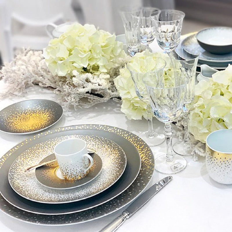 Elegant table setting with gold and silver plates, Souffle d’Or, white flowers, and crystal glasses.