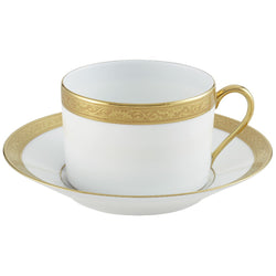 A white porcelain breakfast cup with gold Renaissance style border inlaid, accompanied by a saucer, against a white background.