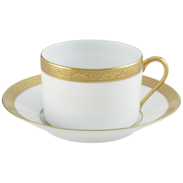 A white porcelain breakfast cup with gold Renaissance style border inlaid, accompanied by a saucer, against a white background.