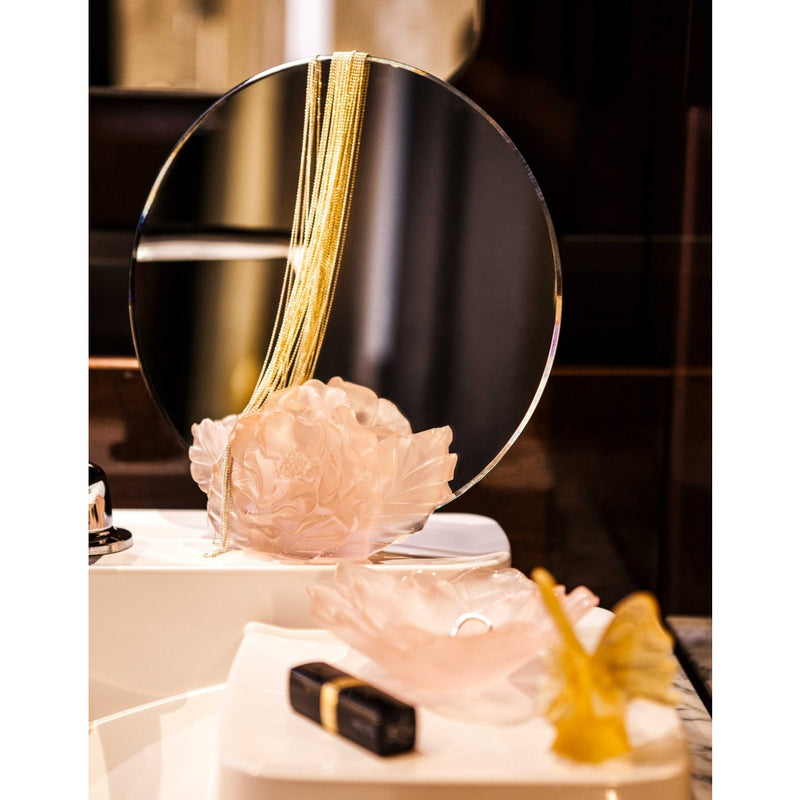 Camelia shape crystal decor styled by a mirror on a white surface