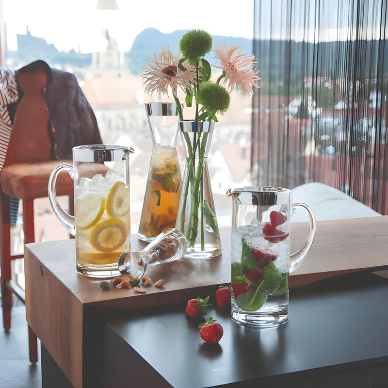 Table with glasses of iced tea and water, a vase with flowers, and strawberries on a wooden surface.