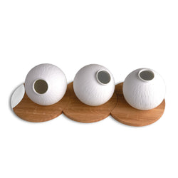 Three white textured vases on wooden stands against a white background
