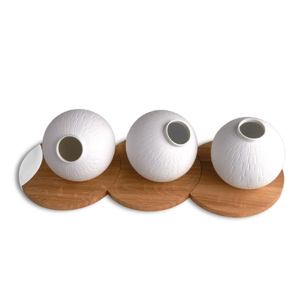 Three white textured vases on wooden stands against a white background