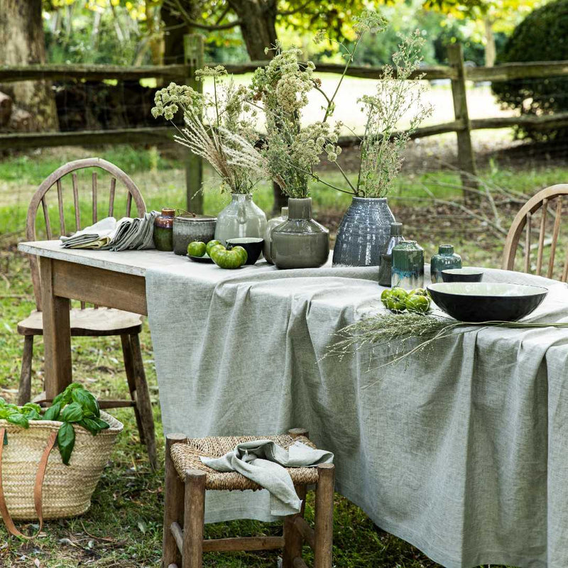 Outdoor table setting with natural elements and rustic chairs.