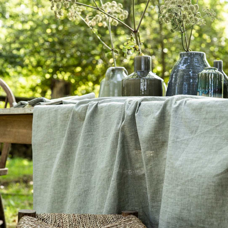 Table with a green tablecloth and decorative vases outdoors