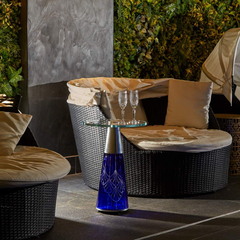 Outdoor seating area with Saint-Rémi crystal champagne flute with fine bevel cuts by Cristallerie de Montbronn on a blue decorative table.