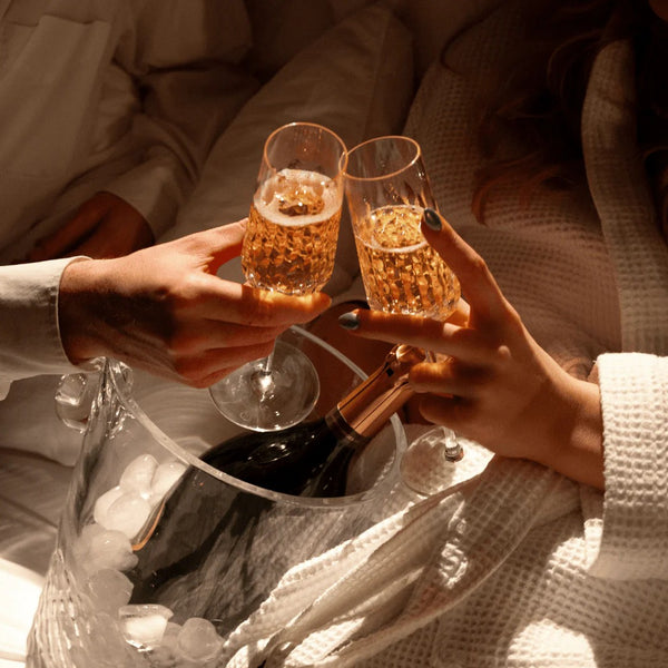 Two persons holding Elegant crystal champagne flute from the Ulysse collection, featuring myth-inspired siren-scale motifs.